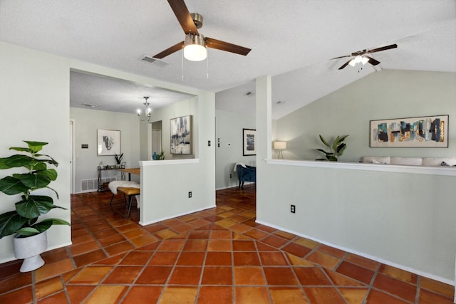 empty room with a textured ceiling, tile patterned flooring, ceiling fan with notable chandelier, visible vents, and vaulted ceiling