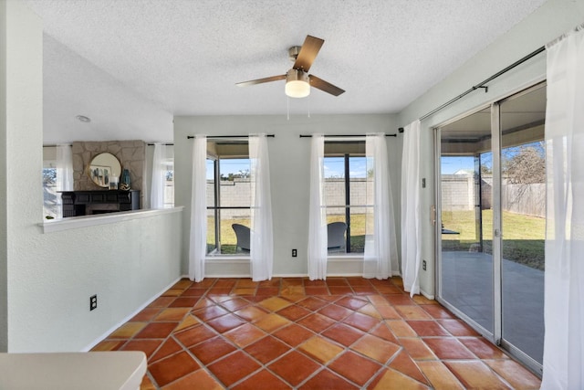 tiled empty room featuring a ceiling fan, a textured ceiling, and a textured wall