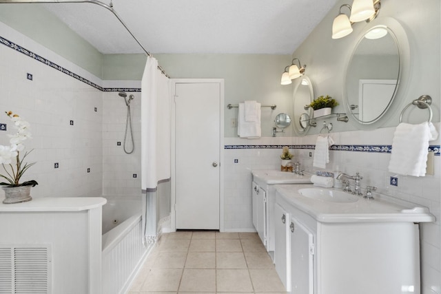 bathroom featuring tile walls, visible vents, shower / bath combo with shower curtain, vanity, and tile patterned flooring