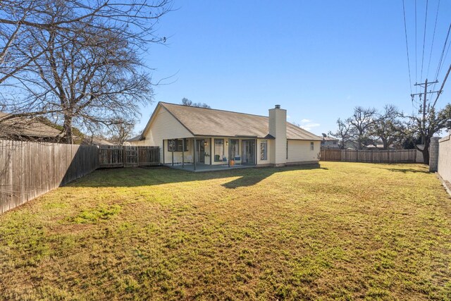 rear view of property with a fenced backyard, a lawn, and a chimney