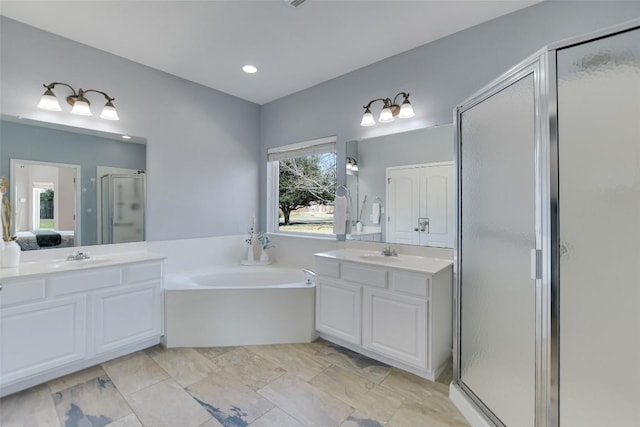 ensuite bathroom with two vanities, a sink, a shower stall, and a bath