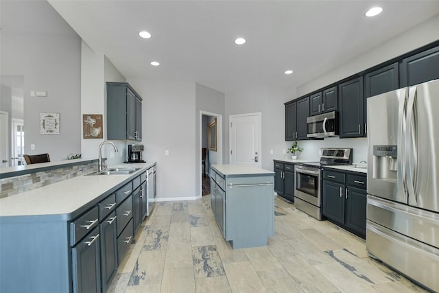 kitchen featuring a peninsula, a sink, light countertops, appliances with stainless steel finishes, and a center island