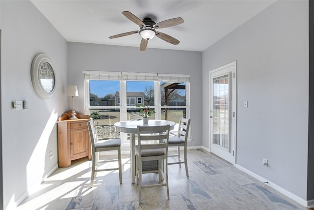 dining space featuring a ceiling fan, a healthy amount of sunlight, and baseboards