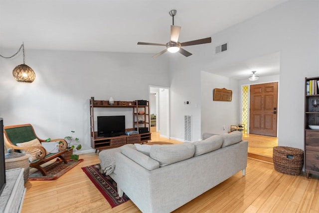 living area featuring light wood-style floors, visible vents, and vaulted ceiling