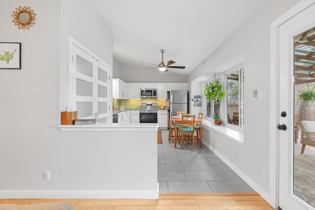 kitchen featuring white cabinets, decorative backsplash, lofted ceiling, ceiling fan, and appliances with stainless steel finishes