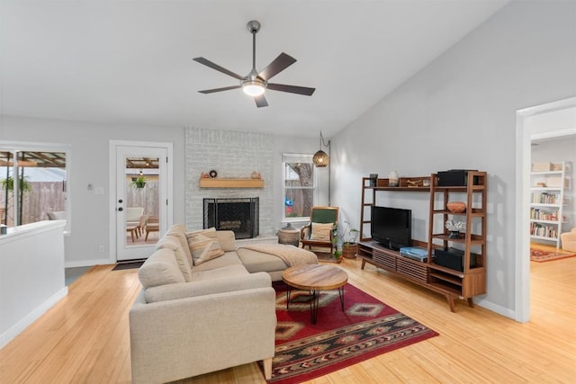 living room with a large fireplace, ceiling fan, vaulted ceiling, and wood finished floors