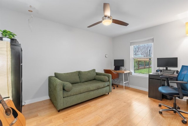 home office with light wood finished floors, a ceiling fan, and baseboards