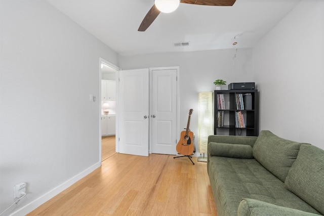 living area featuring baseboards, ceiling fan, visible vents, and light wood-style floors