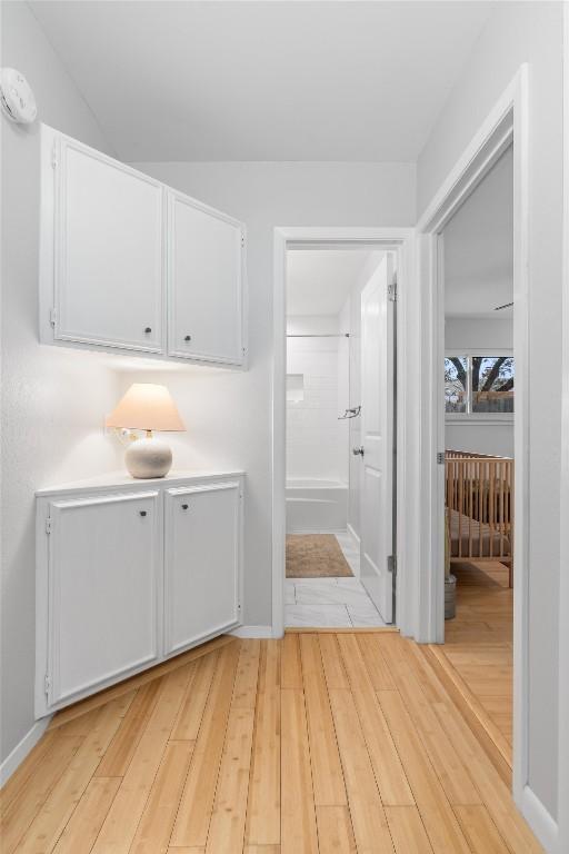 corridor featuring light wood-style floors and baseboards