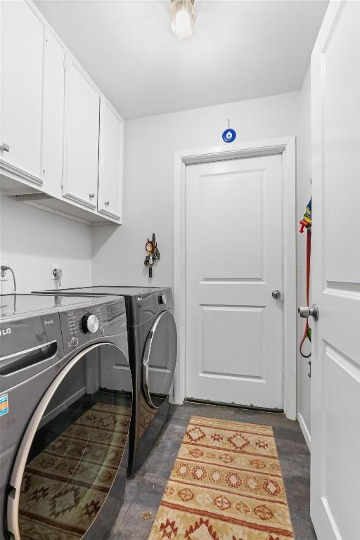 laundry area with dark wood-style floors, washing machine and dryer, and cabinet space