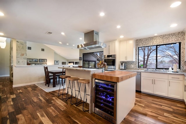 kitchen with beverage cooler, a kitchen island, wood counters, white cabinetry, and island exhaust hood