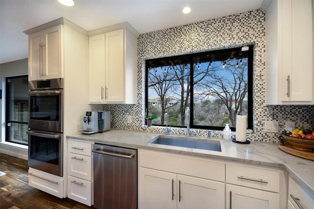 kitchen with decorative backsplash, appliances with stainless steel finishes, dark wood-style flooring, white cabinetry, and a sink