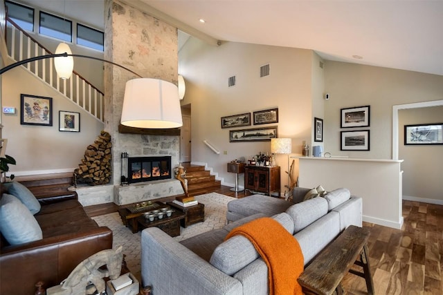 living area with a large fireplace, baseboards, visible vents, stairway, and wood finished floors