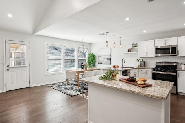 kitchen featuring white cabinets, appliances with stainless steel finishes, light stone countertops, tasteful backsplash, and dark wood finished floors