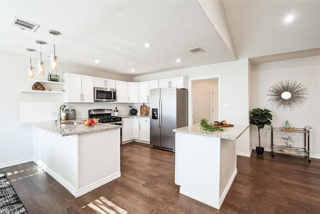 kitchen with stainless steel appliances, a peninsula, a sink, and visible vents