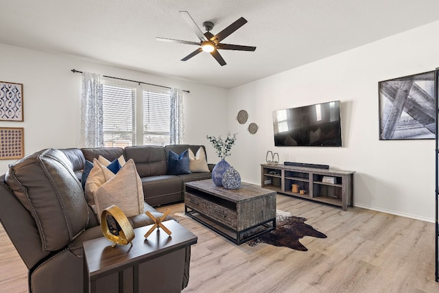 living room with light wood-style floors, ceiling fan, baseboards, and a textured ceiling