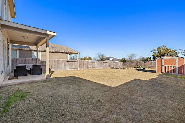 view of yard featuring a patio area, a fenced backyard, a storage unit, and an outbuilding