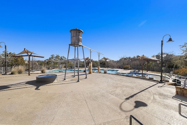 view of jungle gym with a patio, a community pool, and fence