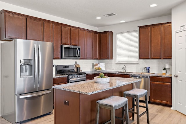 217 Bonnet Blvd, Georgetown, TX 78628 - kitchen featuring stainless steel appliances, a sink, light stone countertops, a kitchen breakfast bar, and a center island