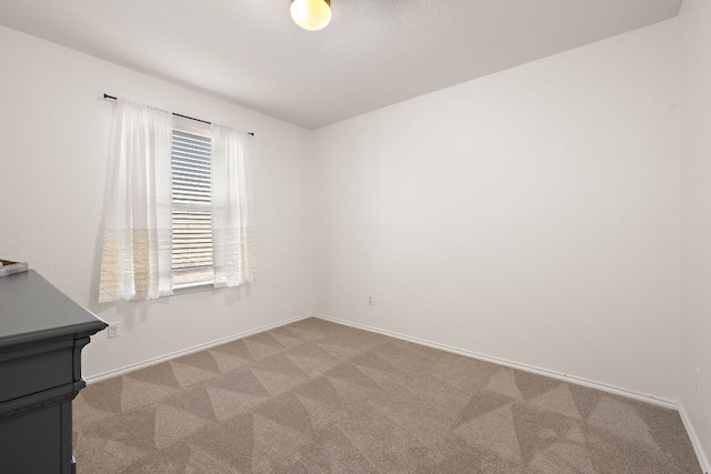 empty room featuring baseboards and light colored carpet