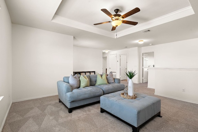 living area with carpet floors, a tray ceiling, ornamental molding, and baseboards