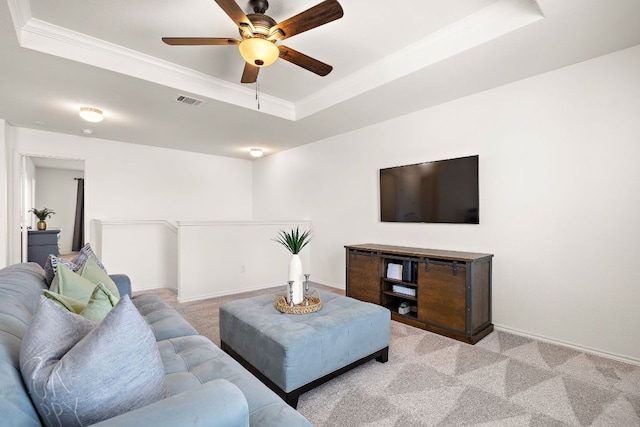 carpeted living room featuring ornamental molding, a tray ceiling, visible vents, and baseboards