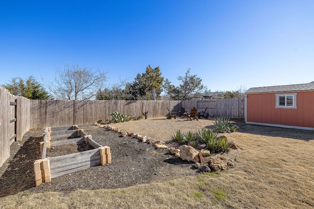 view of yard with a garden, a fenced backyard, and an outbuilding