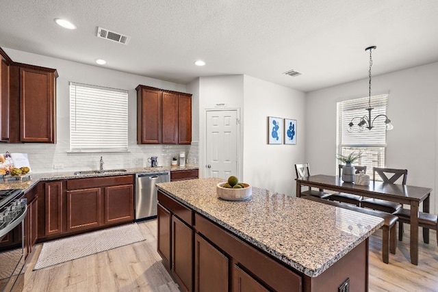 217 Bonnet Blvd, Georgetown, TX 78628 - kitchen with appliances with stainless steel finishes, a sink, light wood-style floors, light stone counters, and a kitchen island