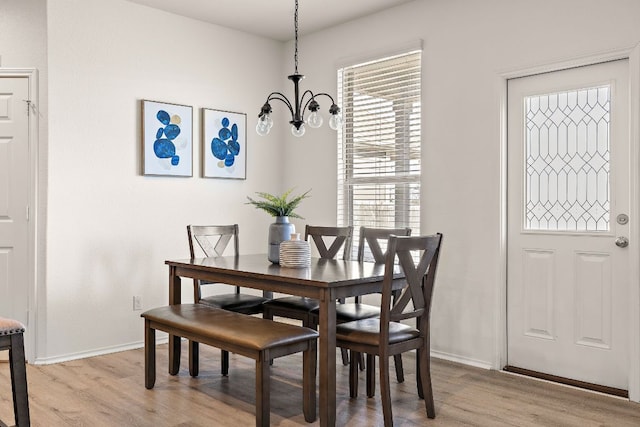 dining space with a notable chandelier, baseboards, and light wood-style floors