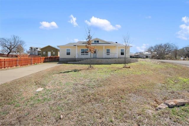 view of front facade with a porch, fence, driveway, and a front lawn