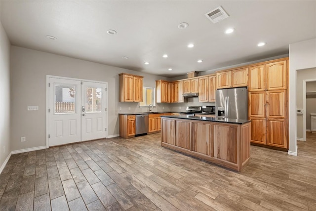 kitchen with a center island, stainless steel appliances, visible vents, a sink, and light wood-type flooring