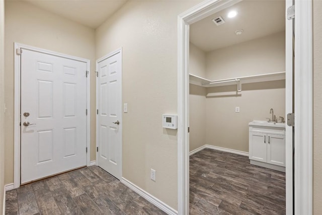 washroom with a sink, baseboards, visible vents, and dark wood-style flooring