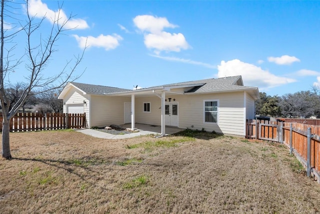 back of house with a fenced backyard, a garage, french doors, a lawn, and a patio area