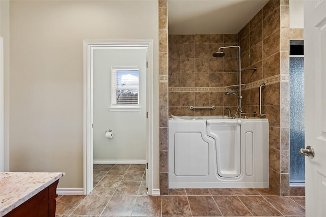 bathroom featuring tile patterned flooring, vanity, baseboards, a shower, and a tub