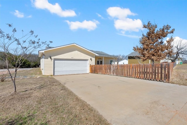 exterior space with an attached garage, fence, and concrete driveway