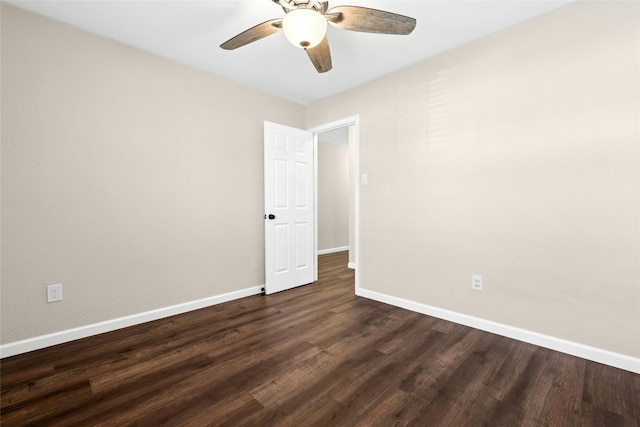 spare room with ceiling fan, dark wood-type flooring, and baseboards