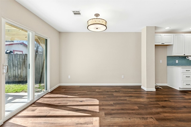 unfurnished dining area with plenty of natural light, baseboards, and dark wood-type flooring