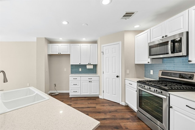 kitchen featuring dark wood finished floors, visible vents, appliances with stainless steel finishes, white cabinetry, and a sink