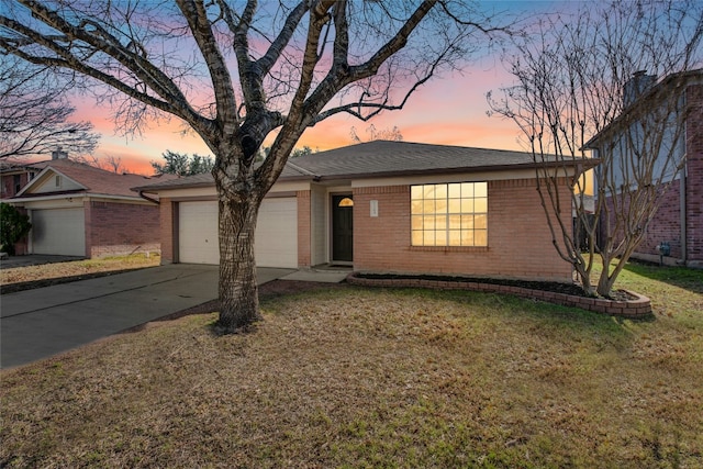 ranch-style home with brick siding, a yard, roof with shingles, concrete driveway, and an attached garage