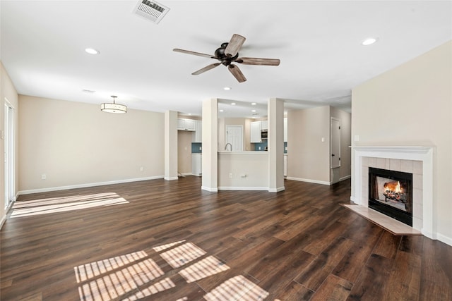 unfurnished living room with dark wood-style floors, baseboards, a fireplace, and visible vents