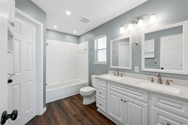 full bathroom with double vanity, a sink, toilet, and wood finished floors