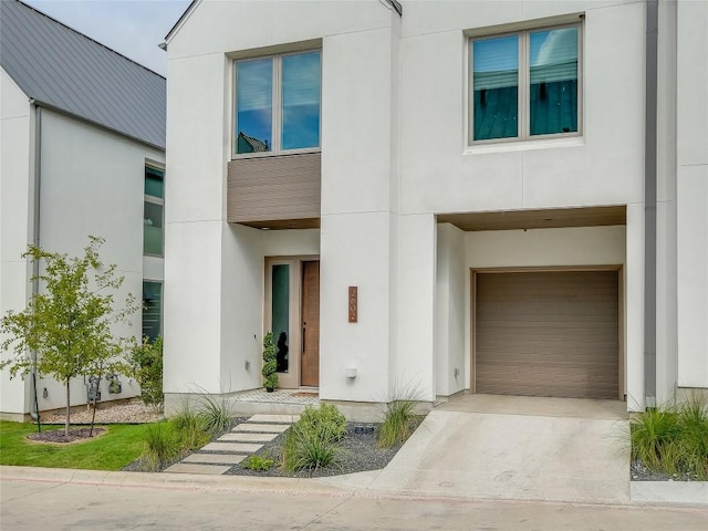 contemporary house with a garage, concrete driveway, and stucco siding