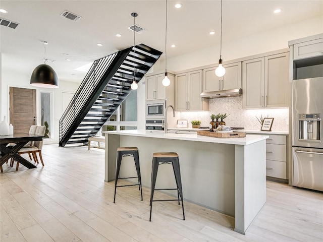 kitchen featuring stainless steel appliances, visible vents, a sink, and under cabinet range hood