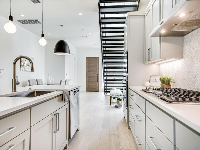 kitchen featuring stainless steel appliances, tasteful backsplash, visible vents, hanging light fixtures, and under cabinet range hood