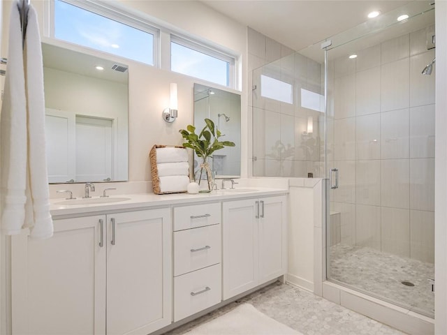 bathroom featuring a stall shower, visible vents, a sink, and double vanity