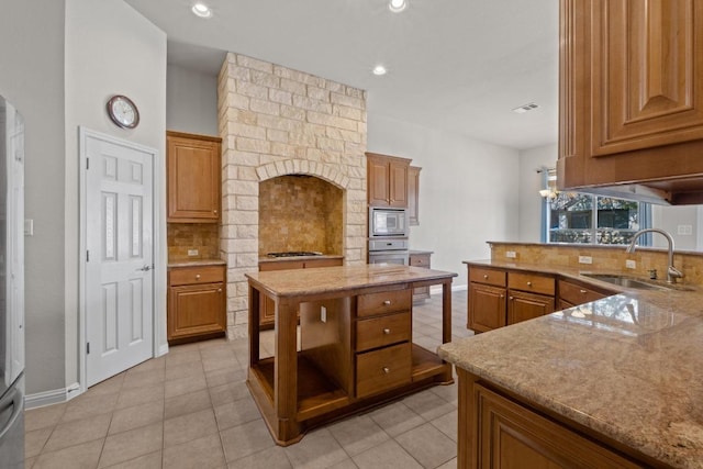 kitchen featuring stainless steel appliances, visible vents, decorative backsplash, brown cabinetry, and a sink