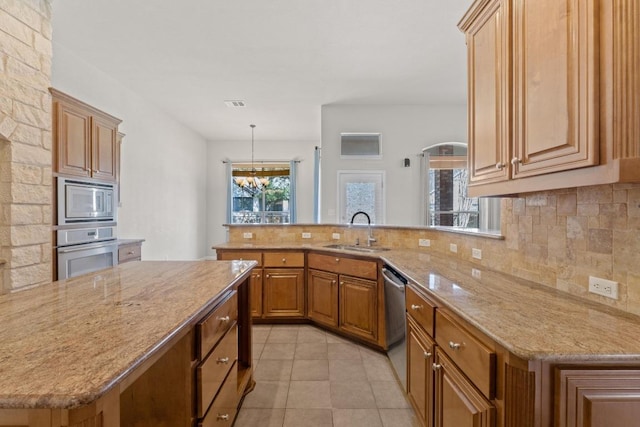 kitchen with appliances with stainless steel finishes, a sink, decorative backsplash, and light stone countertops