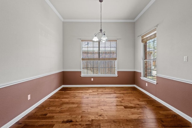 unfurnished dining area with crown molding, a wealth of natural light, a notable chandelier, and wood finished floors