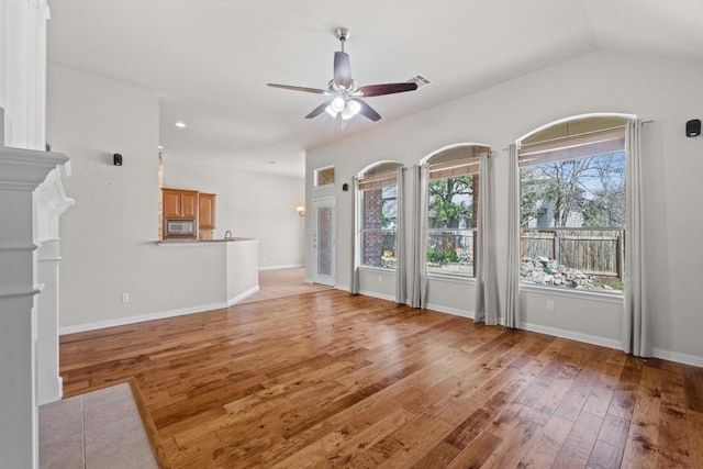 unfurnished living room featuring ceiling fan, light wood finished floors, visible vents, and baseboards