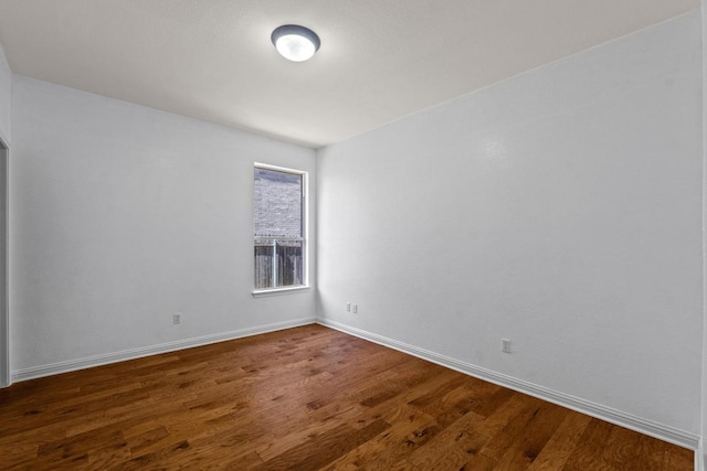 spare room featuring baseboards and dark wood-style flooring